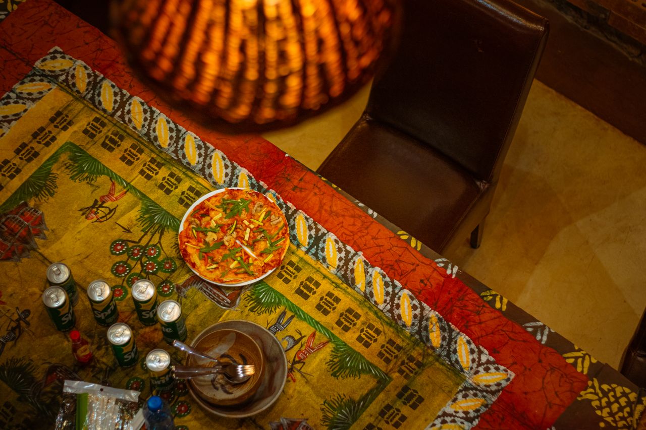 Vibrant top view of a traditional African table with pizza and beverages, creating a lively dining atmosphere.