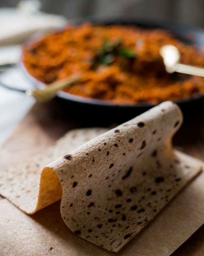Close-up of flatbread set against a blurred, vibrant dish creating a beautiful culinary contrast.
