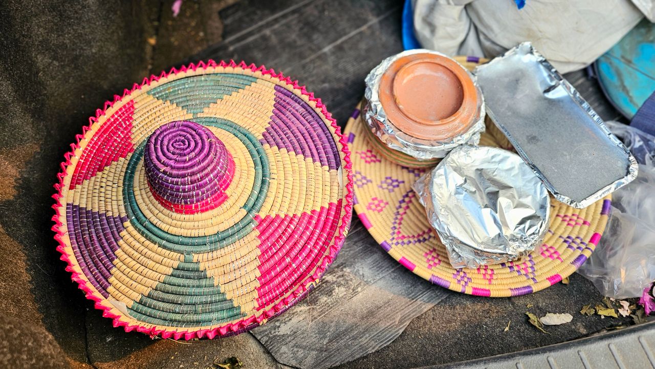 Colorful woven basket with traditional food in clay pots, ready for transport.